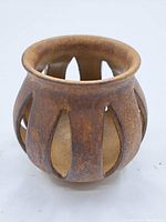 Full side view showing overall shape, color, and cut-out design of pottery candle holder.