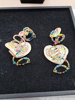 Pair of colorful vintage enameled heart earrings with bead loops in a display box