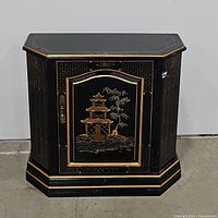 Front view of the black lacquer cabinet with Chinoiserie pagoda and tree decoration in gold.