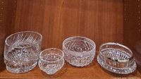Four crystal bowls displayed in a row on wooden shelf showing the different cut patterns and sizes
