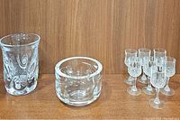 Image of solid clear crystal tall vase, round etched heavy bowl or vase, and seven small crystal wine glasses