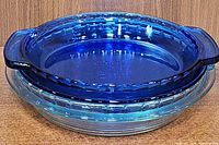 Stack of two cobalt blue glass pie plates showing ribbed edge design and integrated handles.