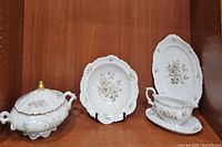 Photo showing the covered round serving bowl, the serving bowl, the platter, and the gravy boat arranged on a wooden surface.