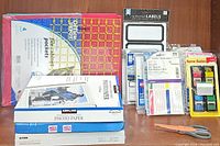 Full lot overview showing photo paper packages, file cabinet pockets, folders, labels, and name badges all arranged on a wood surface.