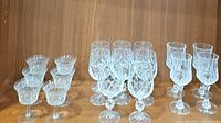 Photo showing 3 groups of stemware on a wooden shelf with 6 etched cordial glasses to the left, 8 Bohemia crystal Bristol cordials in the middle, and 4 crystal wine glasses to the right.