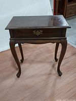 Front angler view of side table showing cabriole legs, drawer with brass pull, and rectangular top.
