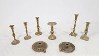 Full view of all eight brass candlesticks and candle holders arranged in a line
