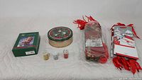 Overview of lot showing box of Christmas cards, round tin, wrapped bundle of red wine gift bags, and three small glitter containers.
