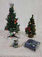 Full view of two table top Christmas trees, night light, and package of lights on white background