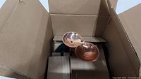 Copper fountain components visible in original cardboard box, showing the leaf-shaped tiers and copper finish.