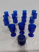 Full view of the lot showing 9 Cristal d'Arques wine glasses, 5 blue water goblets, and 1 cobalt blue jar.