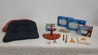 Image showing all items including cushions, wooden pipe holder, scissors, light bulbs, and small household items arranged on a bed.