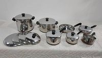 Full set of Revere Ware pots and pans with lids arranged on a surface, showing all pieces included in the lot.