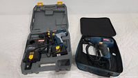 Two Ryobi drills displayed on a white surface: one cordless drill in molded plastic case with charger and battery, the other electric corded drill in a soft case.