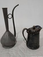 Photo showing both the antique pewter rose water jug and the lidded silver pitcher.