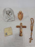 Overview of all spiritual items including Virgin Mary statue, terracotta urn, wooden crucifix, rosary beads, and religious card
