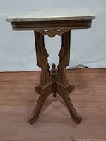 Front side view of Eastlake style Victorian table showing wooden base with carved details and stone top.