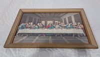 Front view of the framed print of The Last Supper, showing the full artwork and the light wood frame with grooved detailing.
