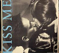 Vinyl single cover of Stephen 'Tintin' Duffy's 'Kiss Me' showing a black and white close-up photo of a man kissing a woman