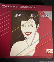 Front cover of the Duran Duran Rio vinyl album showing the stylized female illustration with maroon background and diagonal lines.