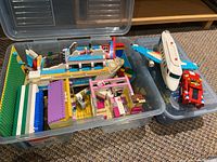 Overview of Lego kits with various partially built models inside two plastic bins.