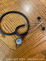 Full view of the black Littmann paediatric double bell stethoscope lying on a wooden surface.