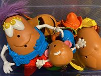 Close up photo showing several large Potato Head toys with some accessories attached and several loose parts.