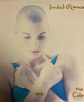 Album cover showing Sinead O'Connor with shaved head and blue top, gold text with album title.
