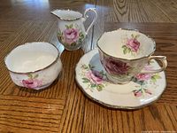 All four pieces displayed on wooden surface showing floral and gold details