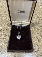 Full view of silver heart-shaped locket and 16-inch chain displayed in a branded box labeled 'Aviva'