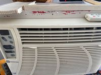 Front view of Maytag window AC showing grille, control panel and remote