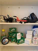 Shelf with hair styling tools (hair dryer, curling iron, flat iron), several bars of Irish Spring soap, Ivory soap bars, bottle of Suave body wash, dish soap, and a container of shaving cream.