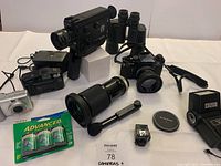 Overall view of all items including cameras, lenses, binoculars, flash and accessories