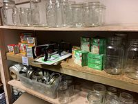 Glass jars, canning rings, and boxed canning lids arranged on wooden shelves