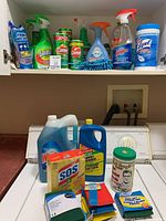 Overview of cleaning supplies on washing machine with various cleaners and accessories