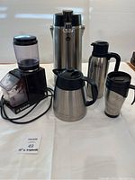 Photo showing all six items including Saeco coffee bean grinder, Starbucks coffee carafe, Nissan travel mug, smaller travel mug, double beverage dispenser, and additional carafe.