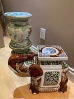 Tall ceramic plant stand with green, blue, and red floral painted decoration and glossy finish.