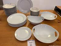 Full lot of white porcelain bowls and plates, multiple sizes visible showing quantity and style.
