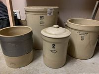 Four Medalta Alberta Potteries stoneware crocks with size markings 10, 5, 2, and one unmarked crock with gray tape. Set shown from front.