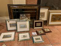Nine framed items on tiled floor including a large wood/gold mirror, framed embossed pictures in assorted frames