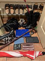 Overview of footwear, handbags, wallets and umbrellas arranged on tile floor