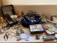Overview of lot with watches, jewelry, mini clocks, trinket boxes and accessories displayed on a table.