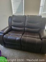 Photo of 2 seater brown leather recliner sofa showing leather cushions, stitching, and recliner footrests.