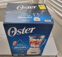 Image of boxed Oster blender showing front and top sides of packaging with blender image and product details.