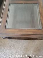 Close-up of wooden center table's glass inset top and wooden frame.