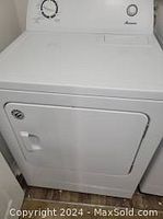 White Amana electric clothes dryer with control knob and start button on the top panel.