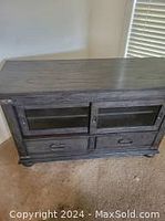 Rectangular wooden TV shelf with two sliding doors above two spacious drawers and metal handles, dark finish, situated on carpet.