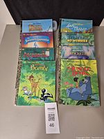 Photo shows eight vintage Little Golden Books with Disney titles arranged in two stacks on a dark background. Titles are clearly visible and books appear in excellent used condition.