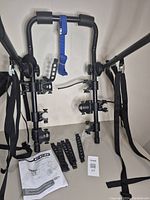 CCM trunk mount bike carrier frame with mounting straps, rubber hooks, and manual laid out on white background.