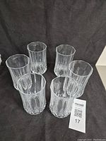Six clear Cristal d'Arques Longchamp water glasses arranged on a dark fabric background, showing the cut-glass vertical fluted detail and diamond-cut bases.